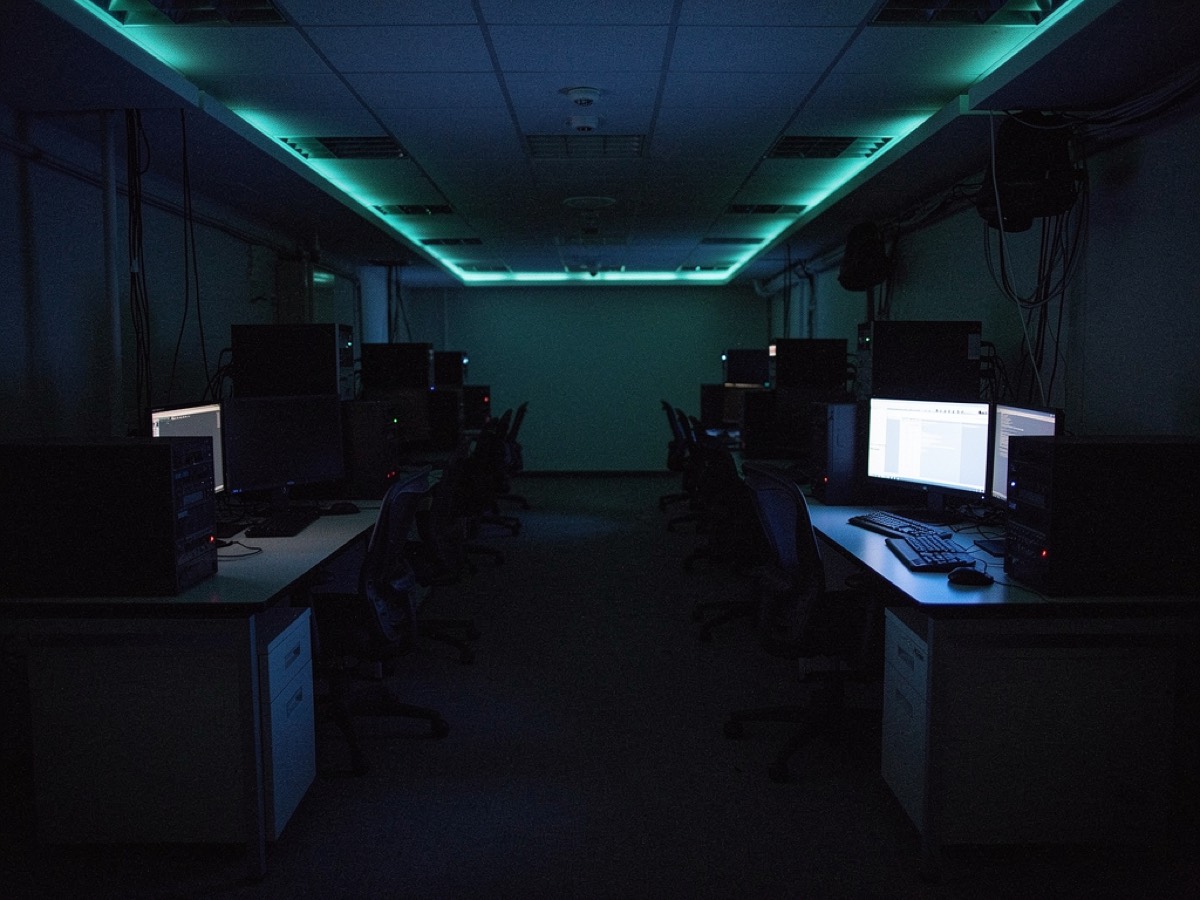A darkened operations room at night with a single workstation still lit